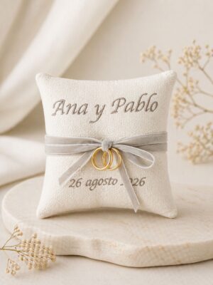 Cojín porta-alianzas bordado con los nombres Ana y Pablo y la fecha de la boda, con lazo para las alianzas