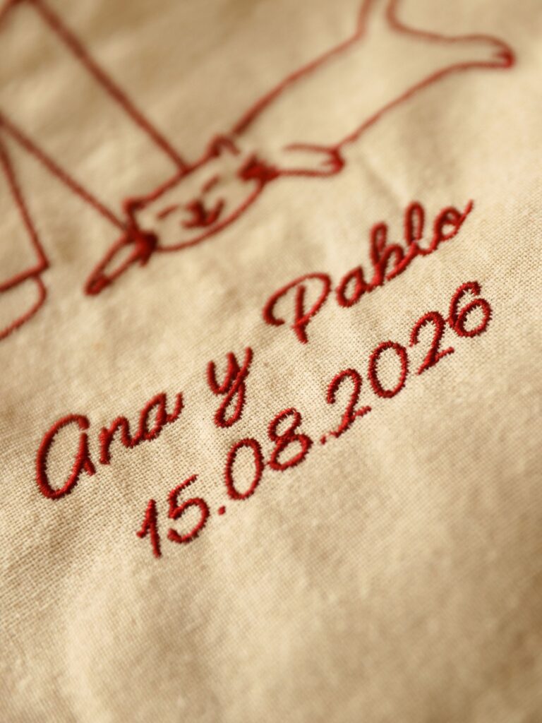 Detalle del bordado con los nombres Ana y Pablo y la fecha de la boda 15.08.2026
