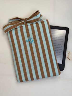 Funda de ebook Ágatha de rayas turquesa y marrón con cierre de lazo, junto a un ebook