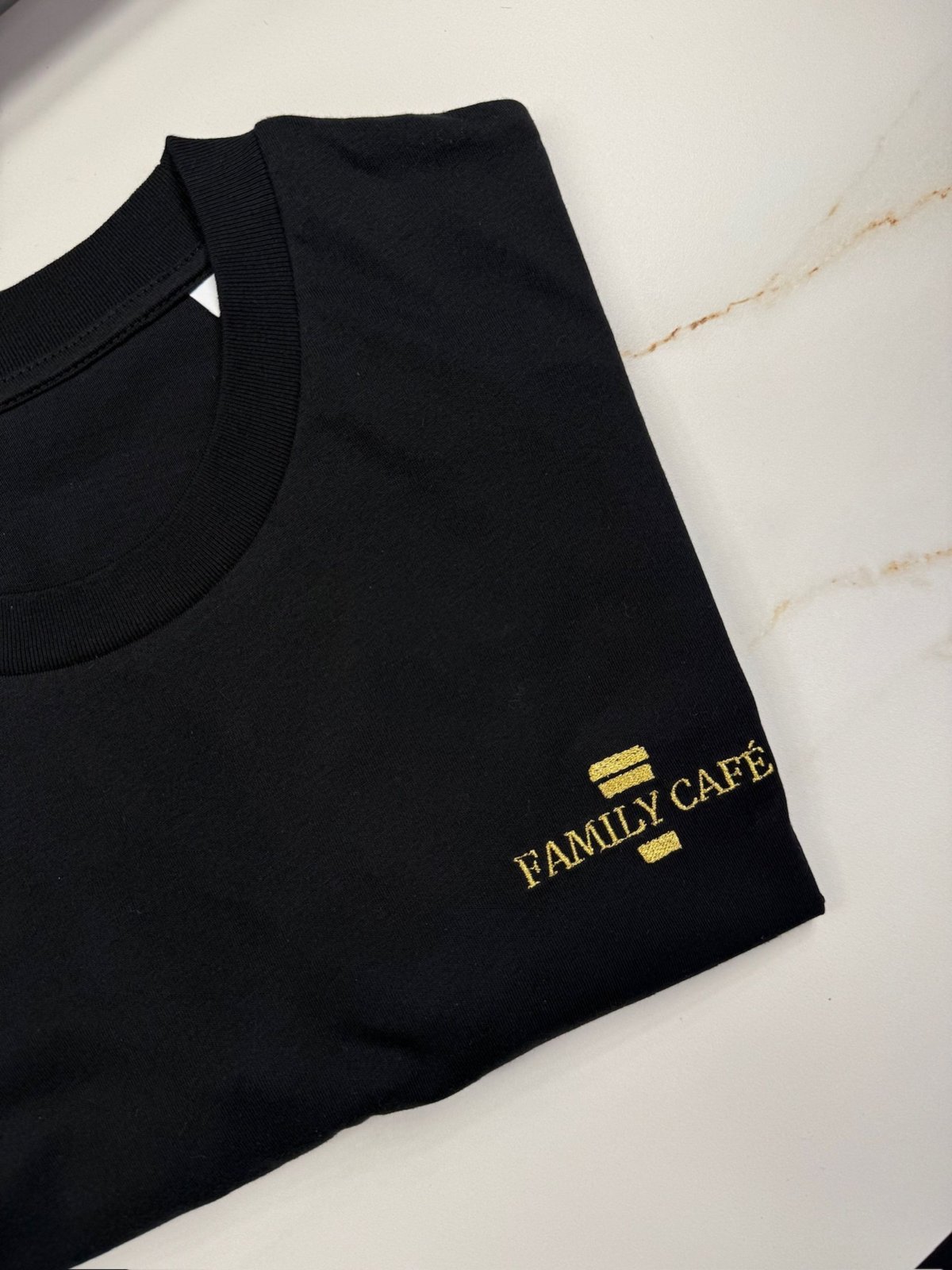 Camiseta negra con logo bordado en dorado para Family Café