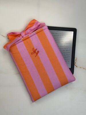 Funda de ebook Ágatha de rayas rosa y naranja con cierre de lazo, junto a un ebook